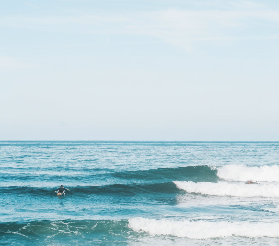 Person surfing on a wave in the ocean with clear blue sky